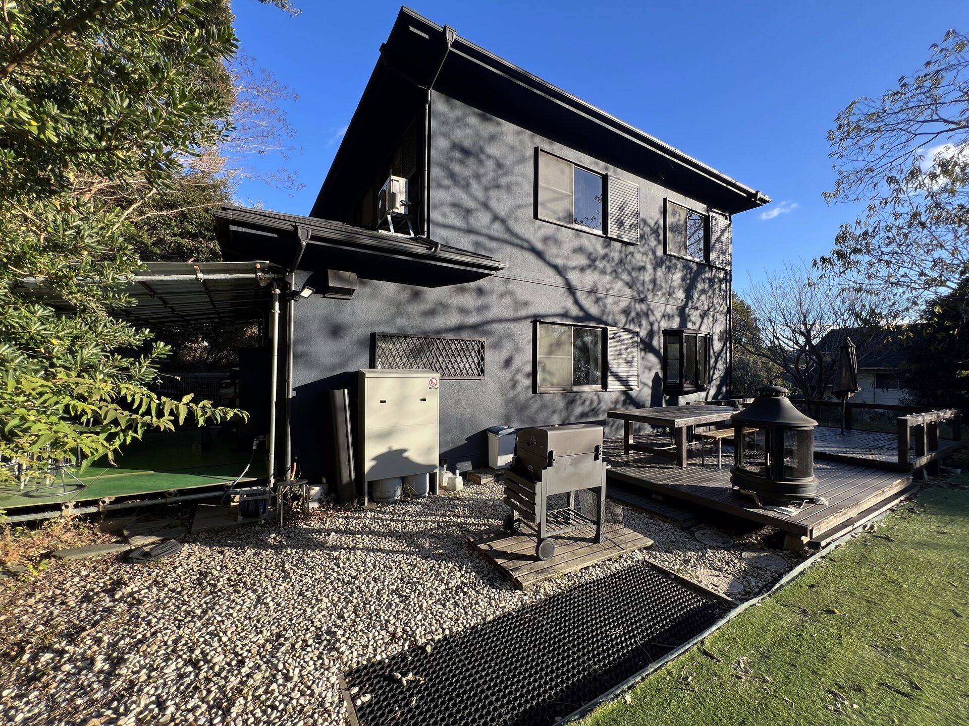 BlueFlow KATSUURA's main house exterior and wooden deck, with a BBQ grill and firepit in the garden